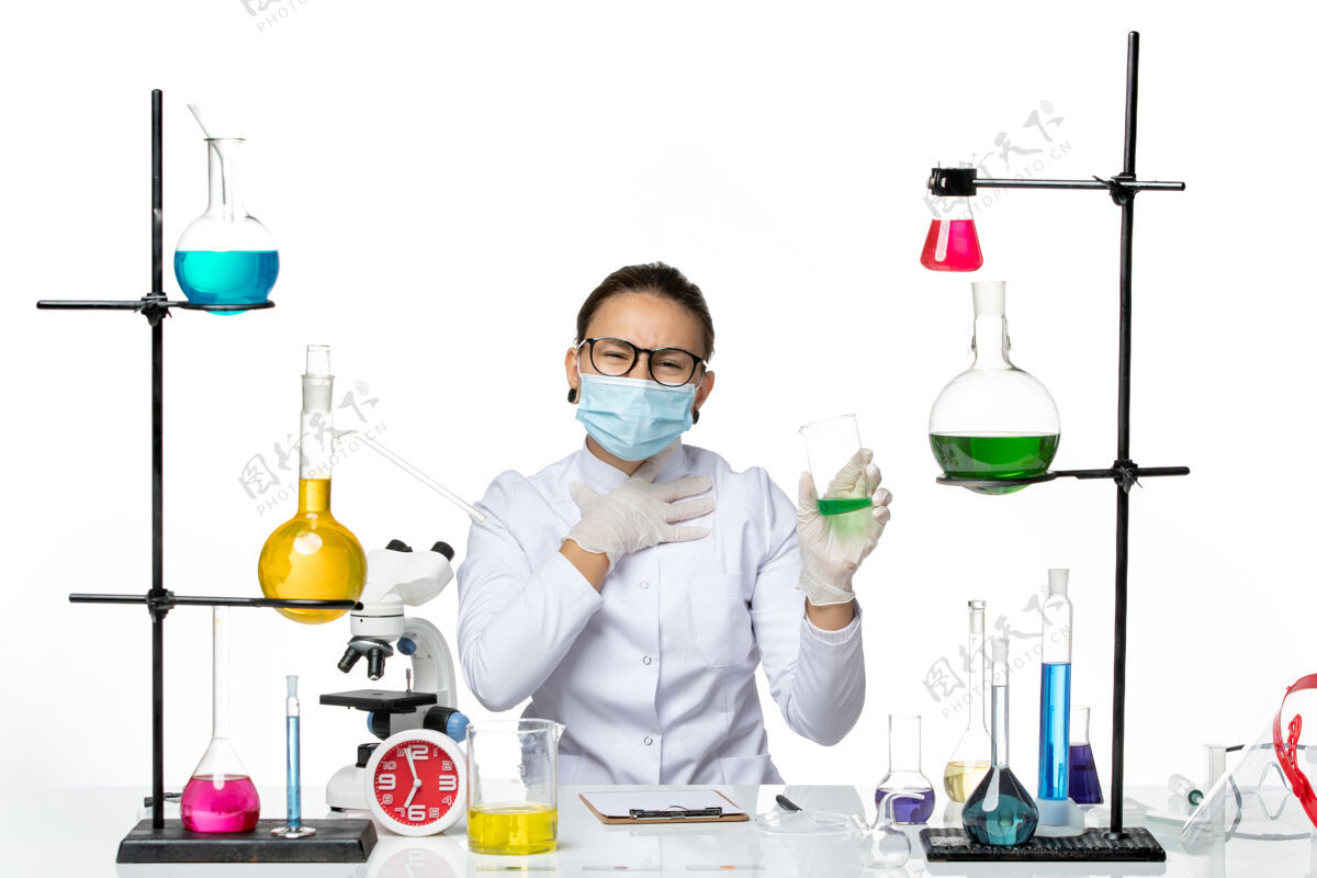 飞溅前视图穿着医疗服的女化学家 戴着面罩 白色背景上有绿色溶液飞溅实验室病毒化学covid-实验室实验室烧杯