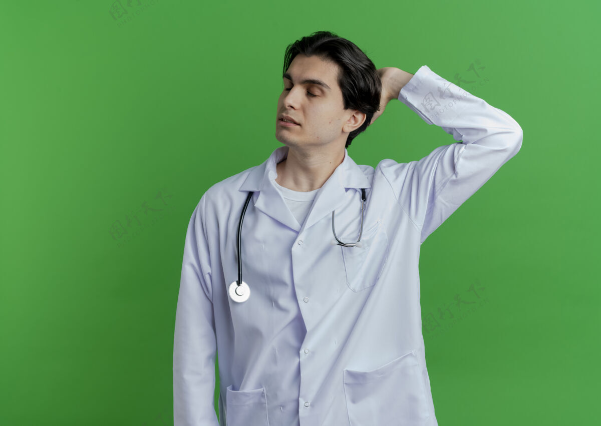 绿色年轻的男医生穿着医用长袍和听诊器 手放在脑后 闭着眼睛长袍眼睛男性