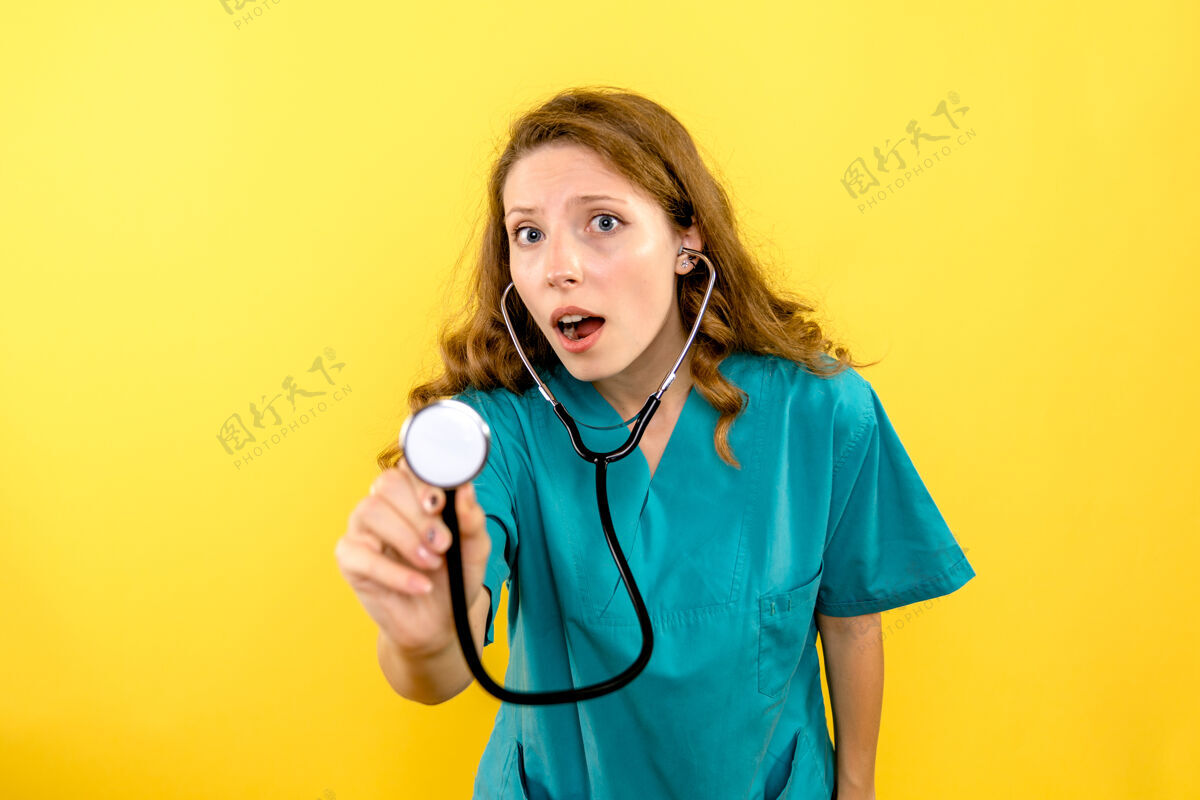 仪器黄色墙上女医生使用听诊器的正面图女病毒专业