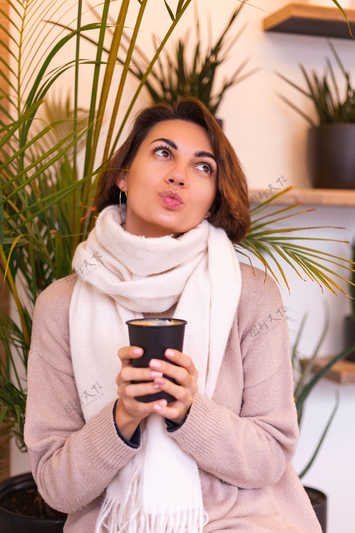 女人一个女孩在舒适的咖啡馆里用一杯热咖啡取暖时尚杯子微笑