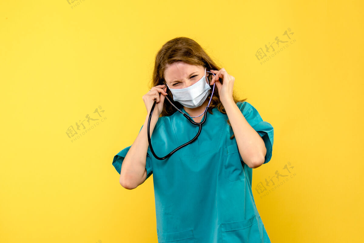 成人黄色地板上戴着口罩的女医生的正视图医院医疗保健黄色人制服