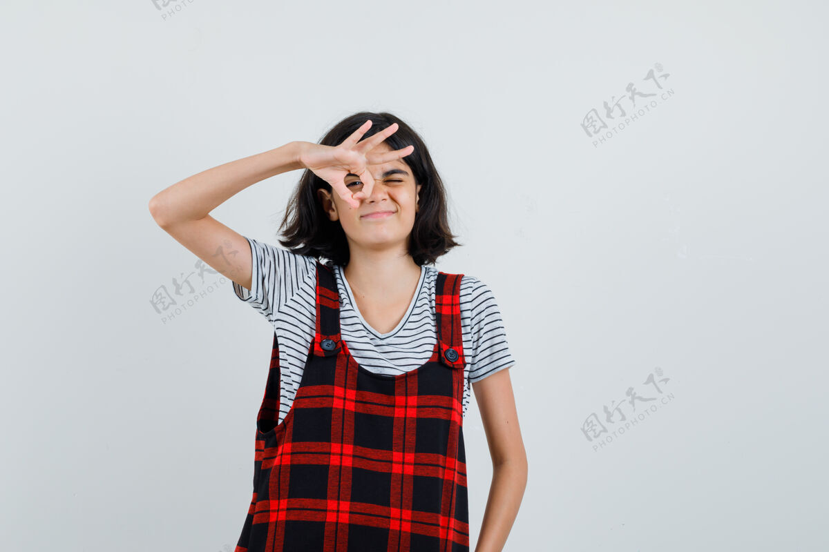 自信穿t恤的未成年女孩在她的眼睛上显示ok手势手势模特表情