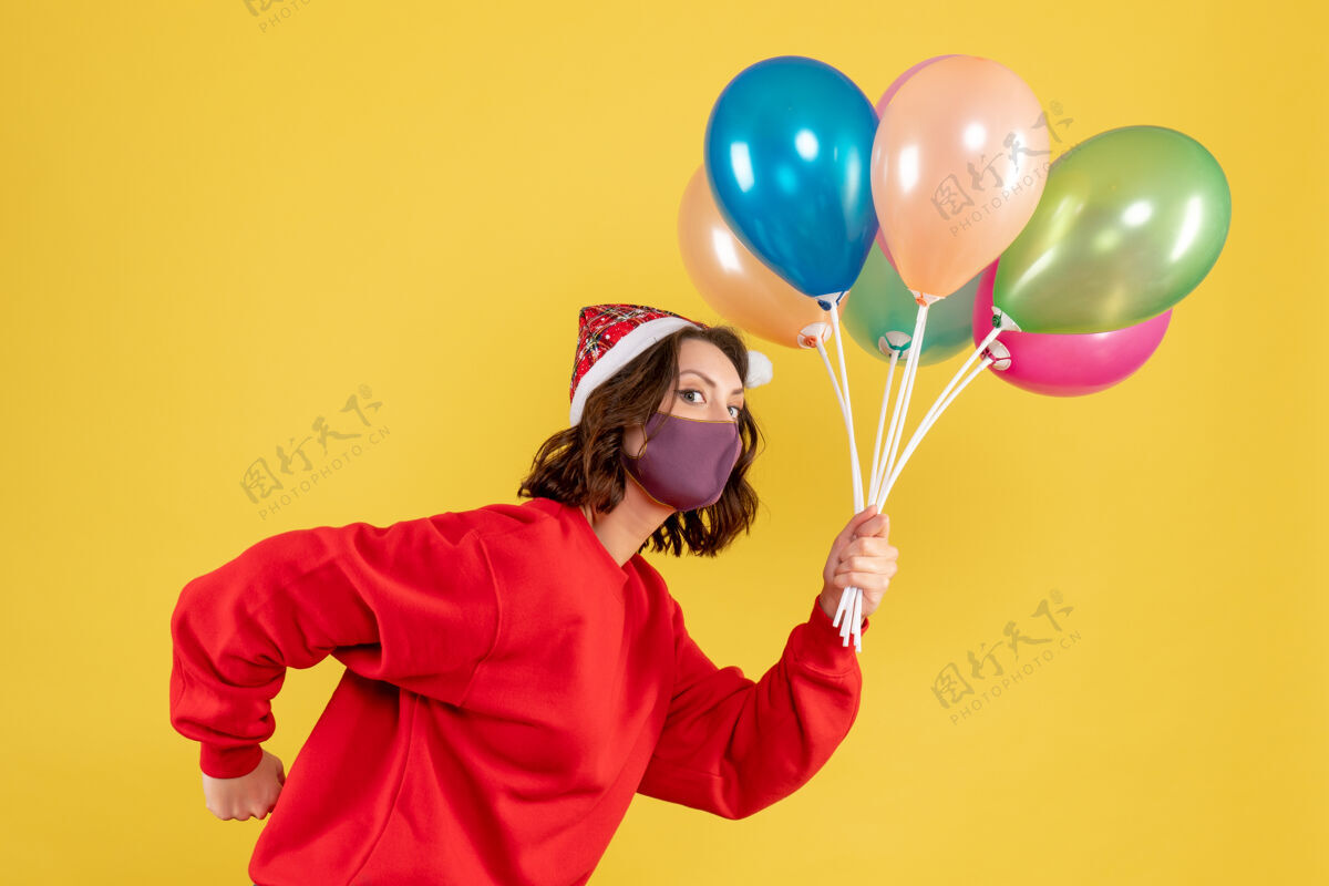黄色正面图年轻女性拿着气球 戴着黄色的无菌面具面具快乐节日