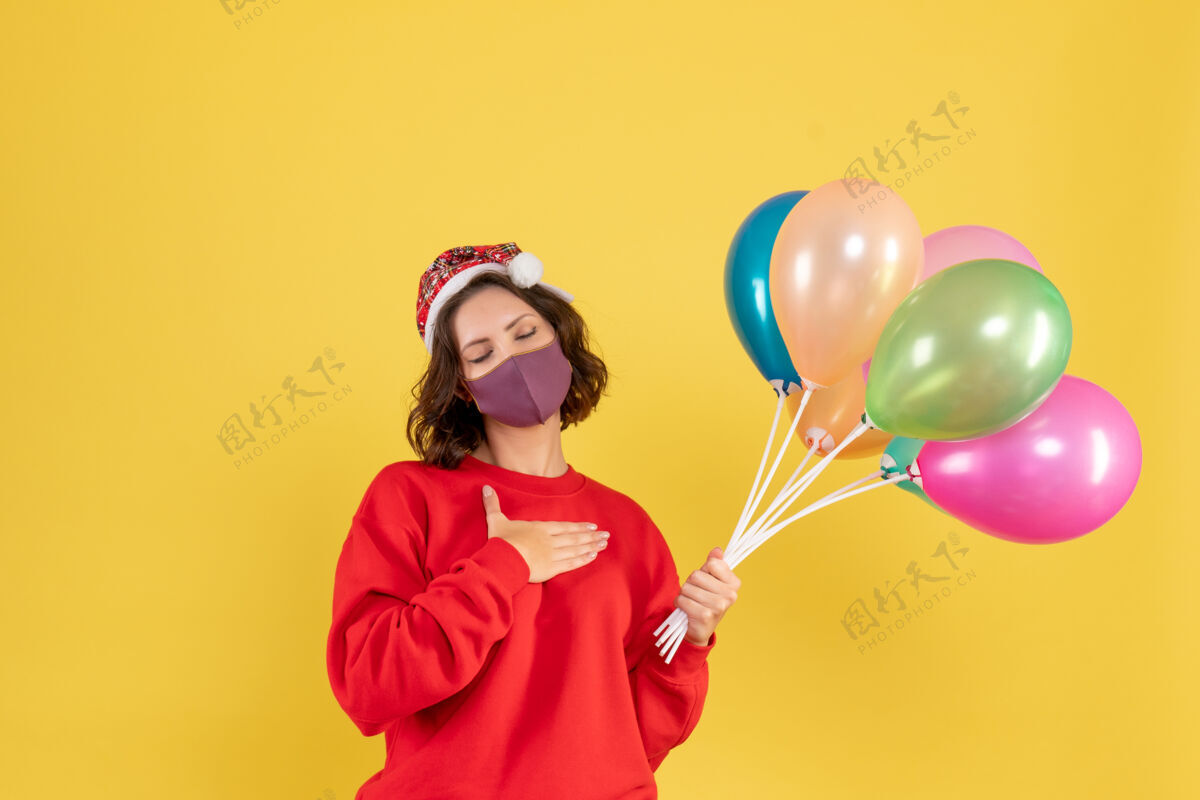 氧气正面图年轻女性拿着气球 戴着黄色的无菌面具面具圣诞节生日