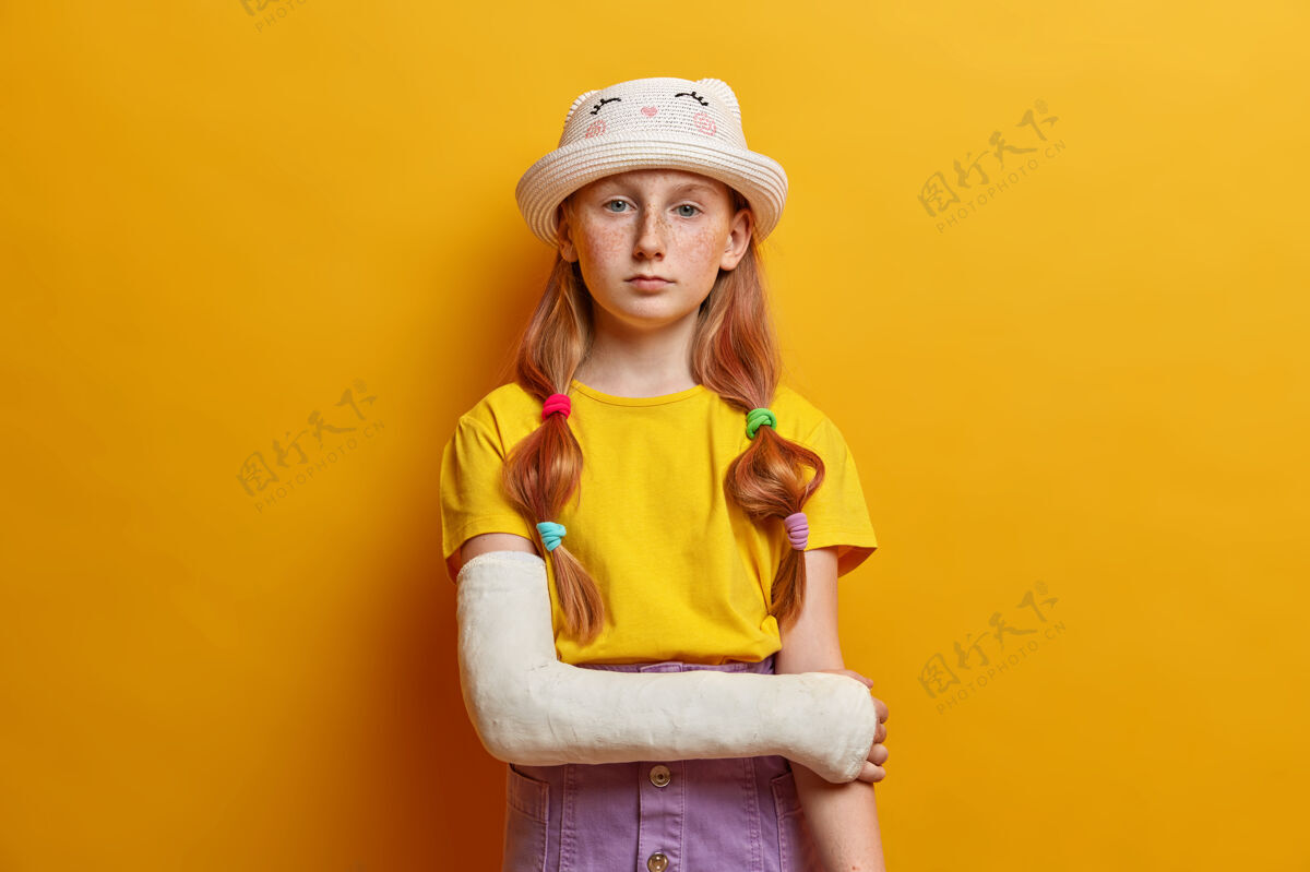 表情冷静严肃的小女孩 长着姜黄色的长发和雀斑皮肤 穿着时髦的夏装 随手摆造型 出事后康复 隔着黄色的墙壁小保险心烦