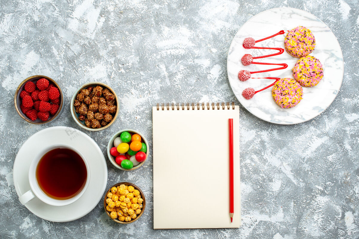 蛋糕俯视不同的糖果和坚果饼干和一杯茶在白色空间早餐糖果茶