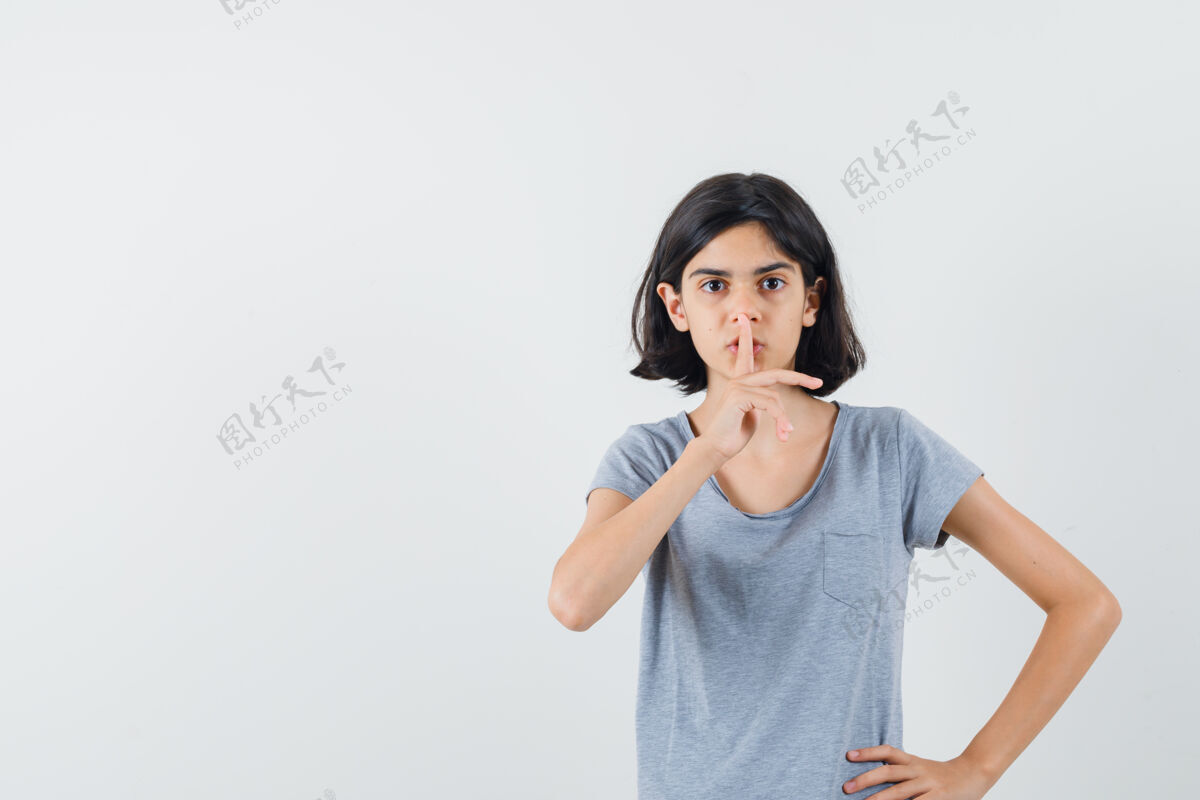 肖像小女孩在t恤衫上显示出沉默的姿态 看上去很小心 正面视图人手势房间