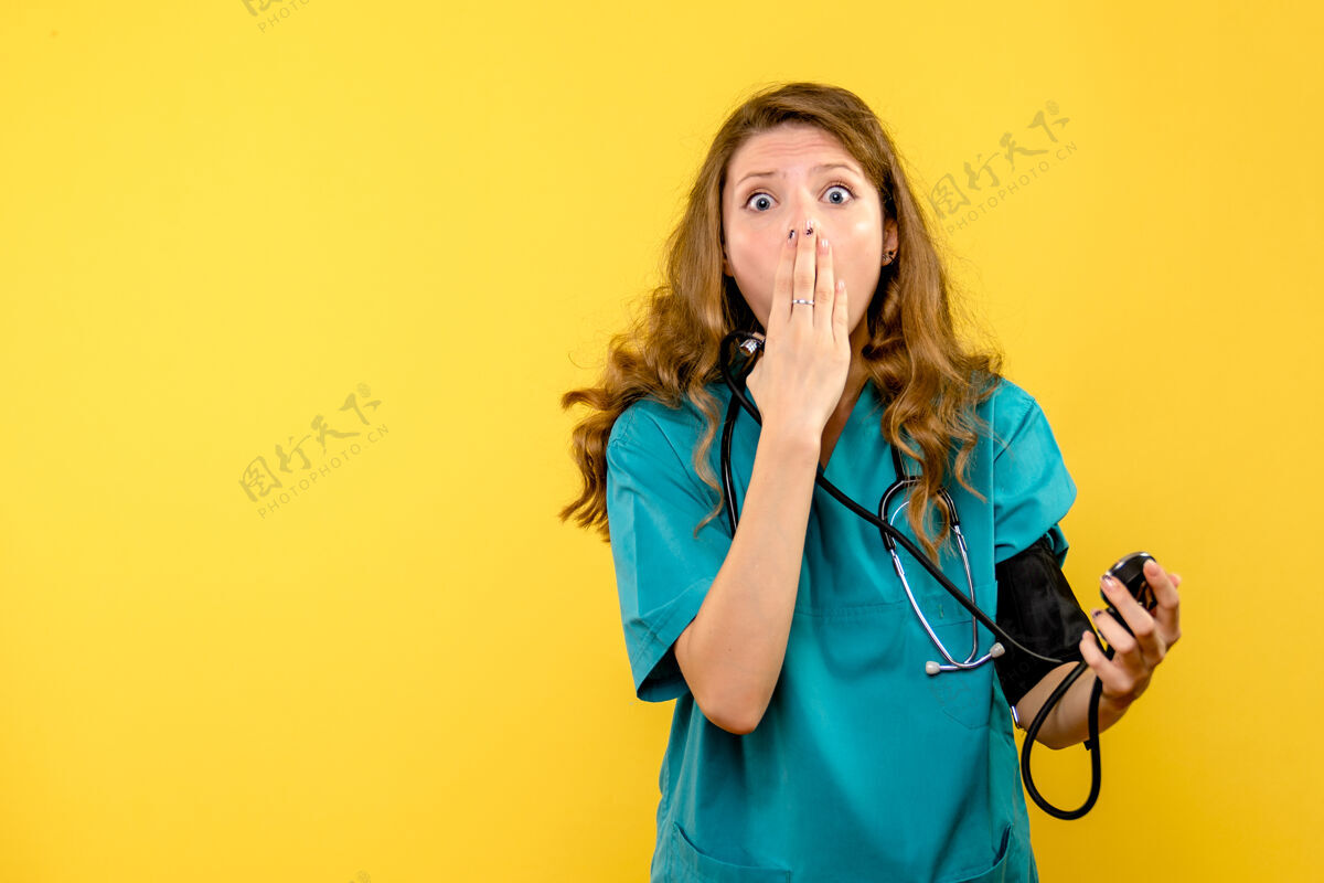 测量女医生在黄色墙壁上测量压力的正面图医疗器械保健人
