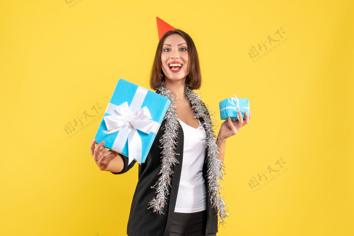 头发圣诞气氛与骄傲的商务女士西装与xsmas帽子显示她的礼物在黄色圣诞节礼物西装