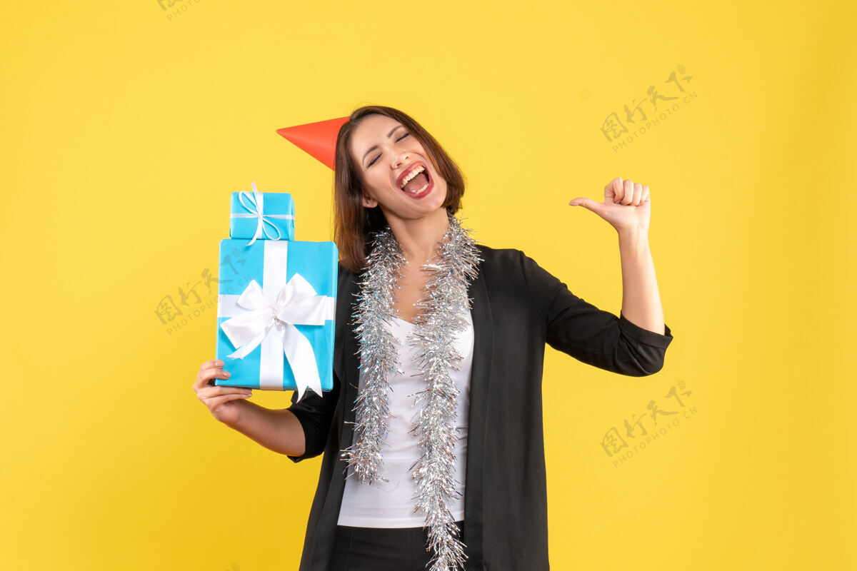 举行圣诞节心情愉快 情绪激动 美丽的女士戴着圣诞帽 拿着黄色的礼物时尚圣诞节漂亮