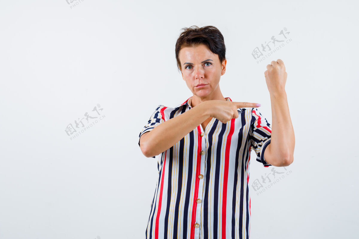 人穿条纹上衣的成熟女人握紧拳头 用食指指着它 看起来很自信 前视图活跃前面信心