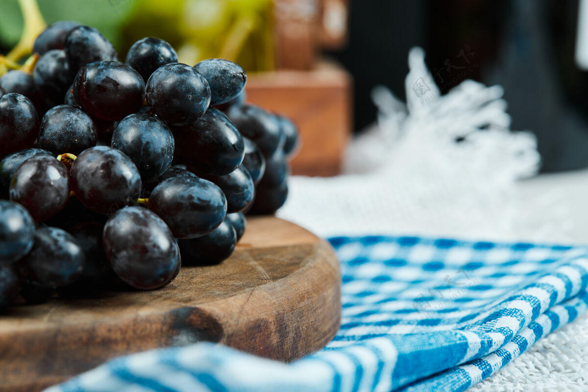 大自然一簇黑葡萄放在木板上 蓝色桌布高质量的照片成熟餐桌黑的