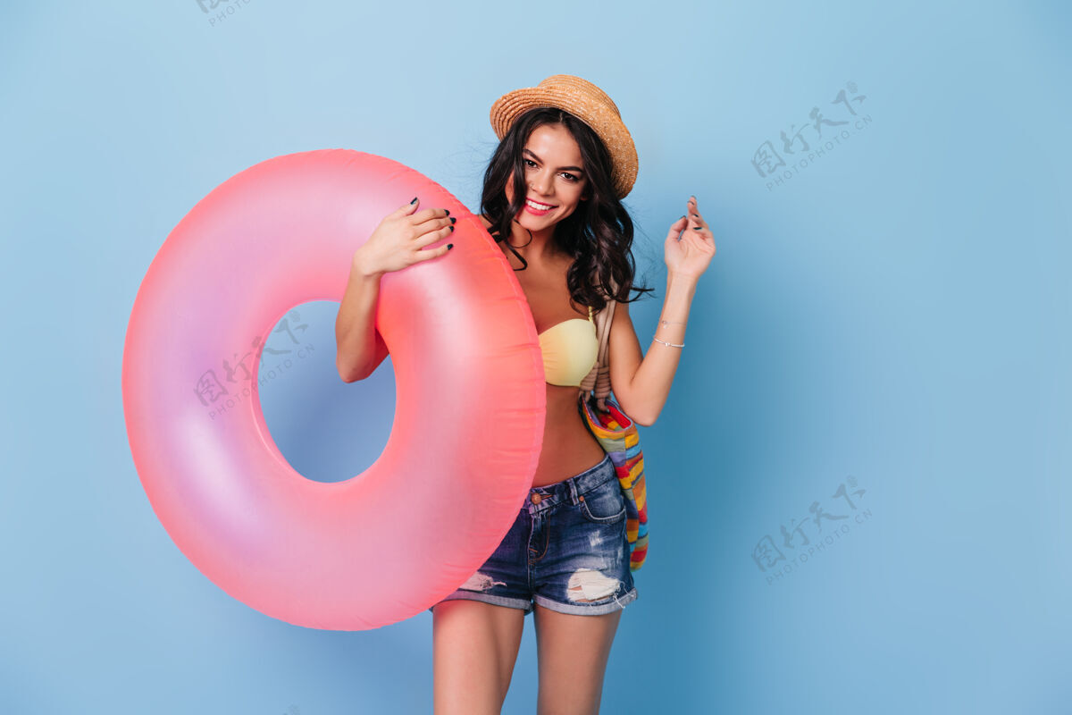 休闲时尚的棕褐色女人拿着粉红色的游泳圈包极乐人