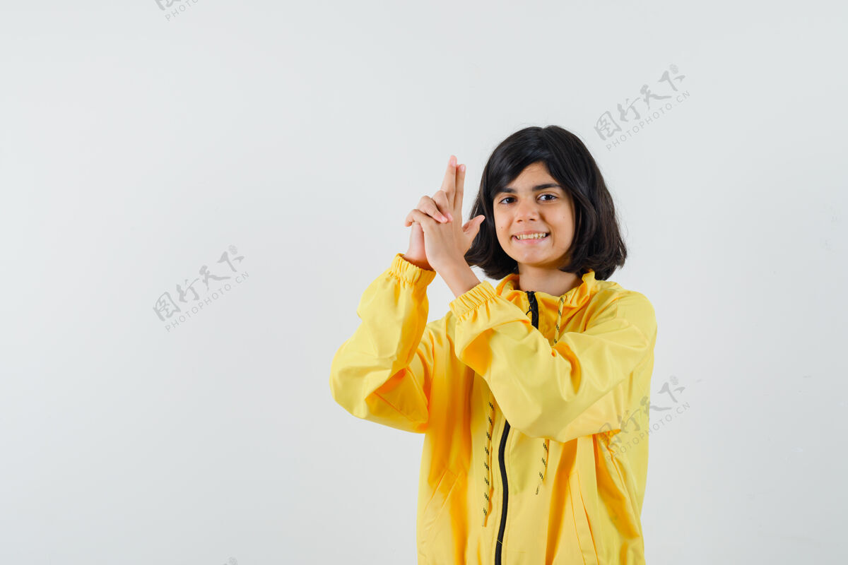 枪穿着黄色连帽衫的小女孩展示着枪的姿势 看起来很自信 正面视图乐趣人欢呼