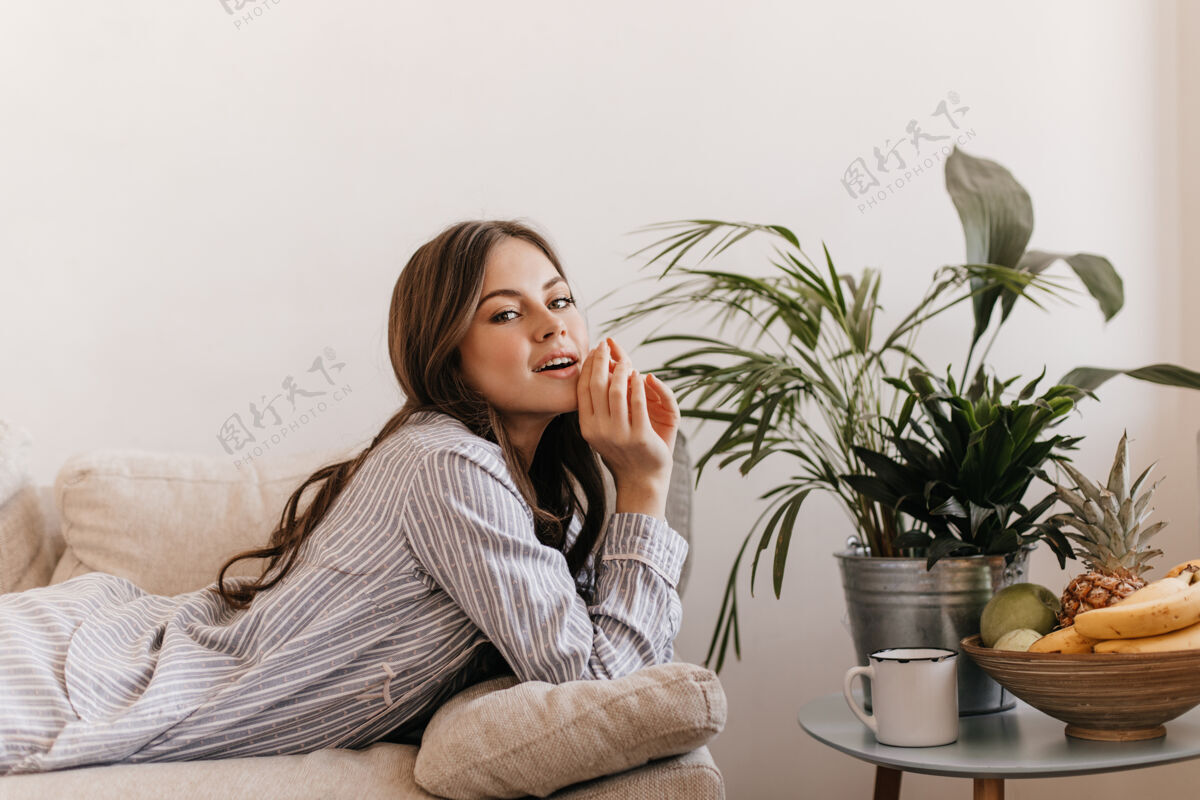 坐着穿着条纹睡衣的女士在客厅休息女士躺在水果盘旁边的沙发上孤独休息漂亮