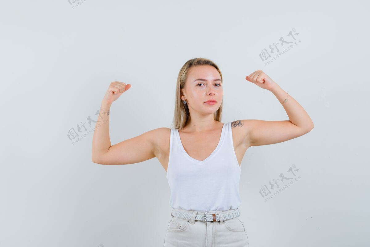 肌肉金发女士在单身 裤子显示肌肉的手臂和看起来自信 前视图健康皮肤女性
