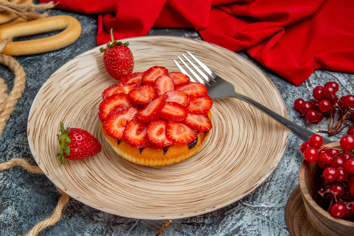 节食正面是美味的草莓蛋糕和浆果在黑暗的表面甜点盘子餐