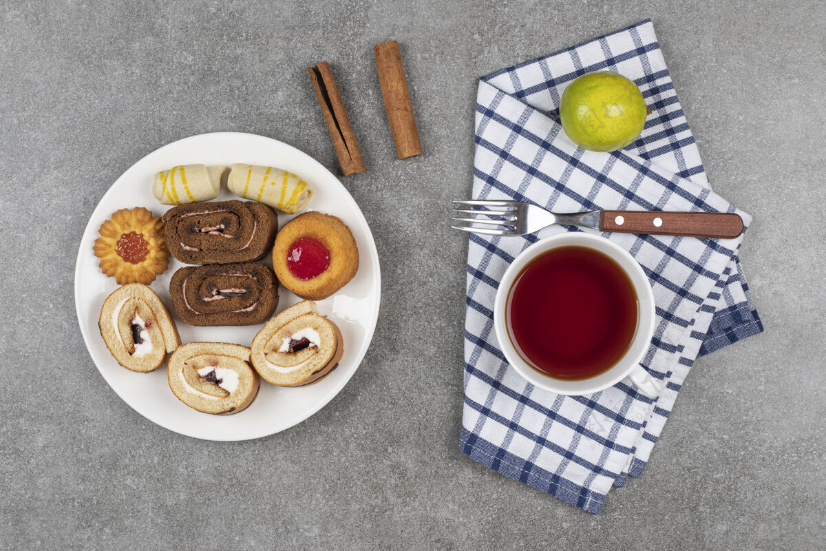 桌布各种美味的饼干放在白盘子里 配上一杯茶面包卷柠檬甜点
