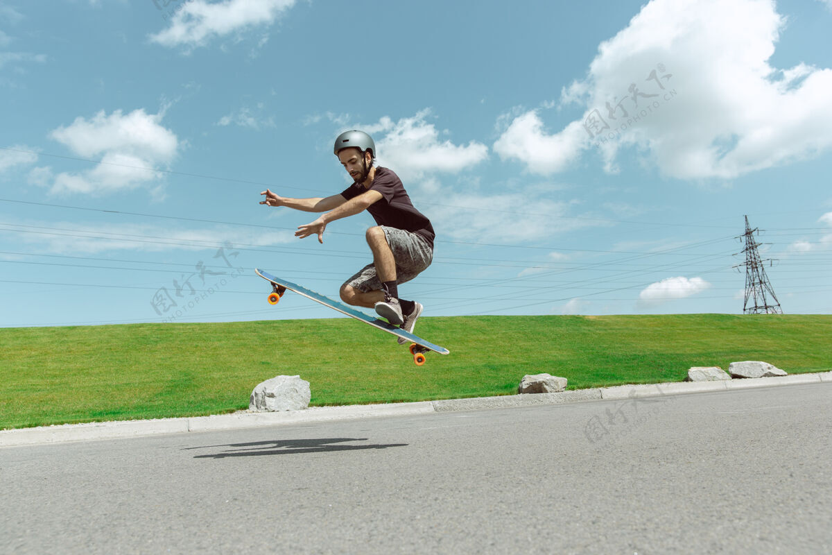 锻炼在阳光明媚的日子里 在城市街道上玩滑板的人年轻人在草地附近骑马 玩长板休闲活动 运动 极限 爱好和运动的概念滑板乐趣极限