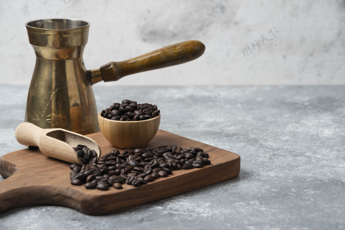 碗黑烤咖啡豆和咖啡机放在木制砧板上烤豆类自然