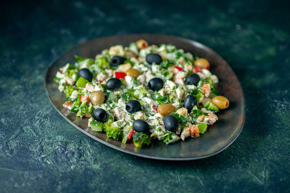 胡椒前视图蔬菜沙拉 深蓝色表面上有梅耶奈斯和橄榄 餐色为假日健康菜照片晚餐前面食物风景