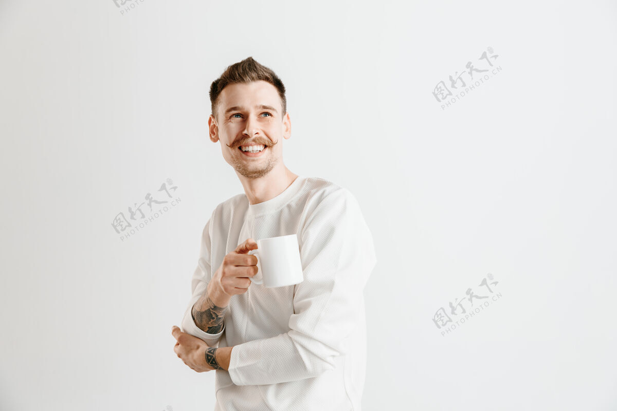 优雅喝咖啡休息一下帅哥拿着咖啡杯站在灰色的工作室背景下领导英俊成人