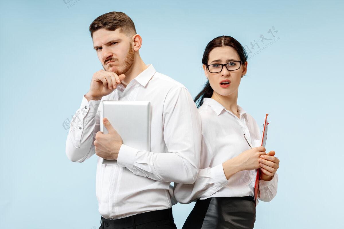工作商业伙伴关系的概念在工作室蓝色背景下看起来可疑的年轻男女伙伴关系微笑个人