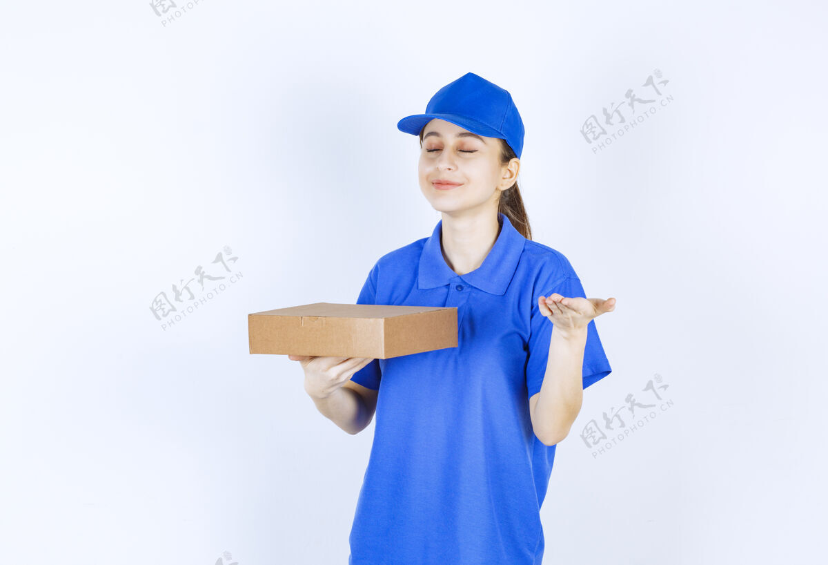 服务穿着蓝色制服的女孩拿着一个纸板外卖盒 闻着食物的味道工人员工女性