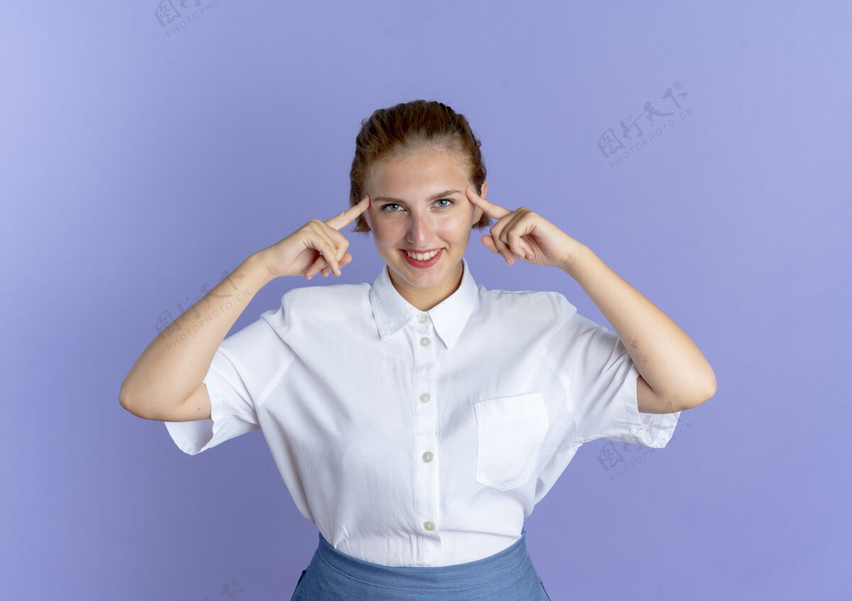 俄国人年轻的微笑金发俄罗斯女孩把手指放在头上紫色背景与复制空间隔离头手指金发