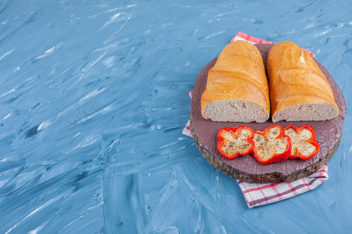 面包把胡椒片和面包放在茶巾的木板上 蓝色的面粉好吃的酵母