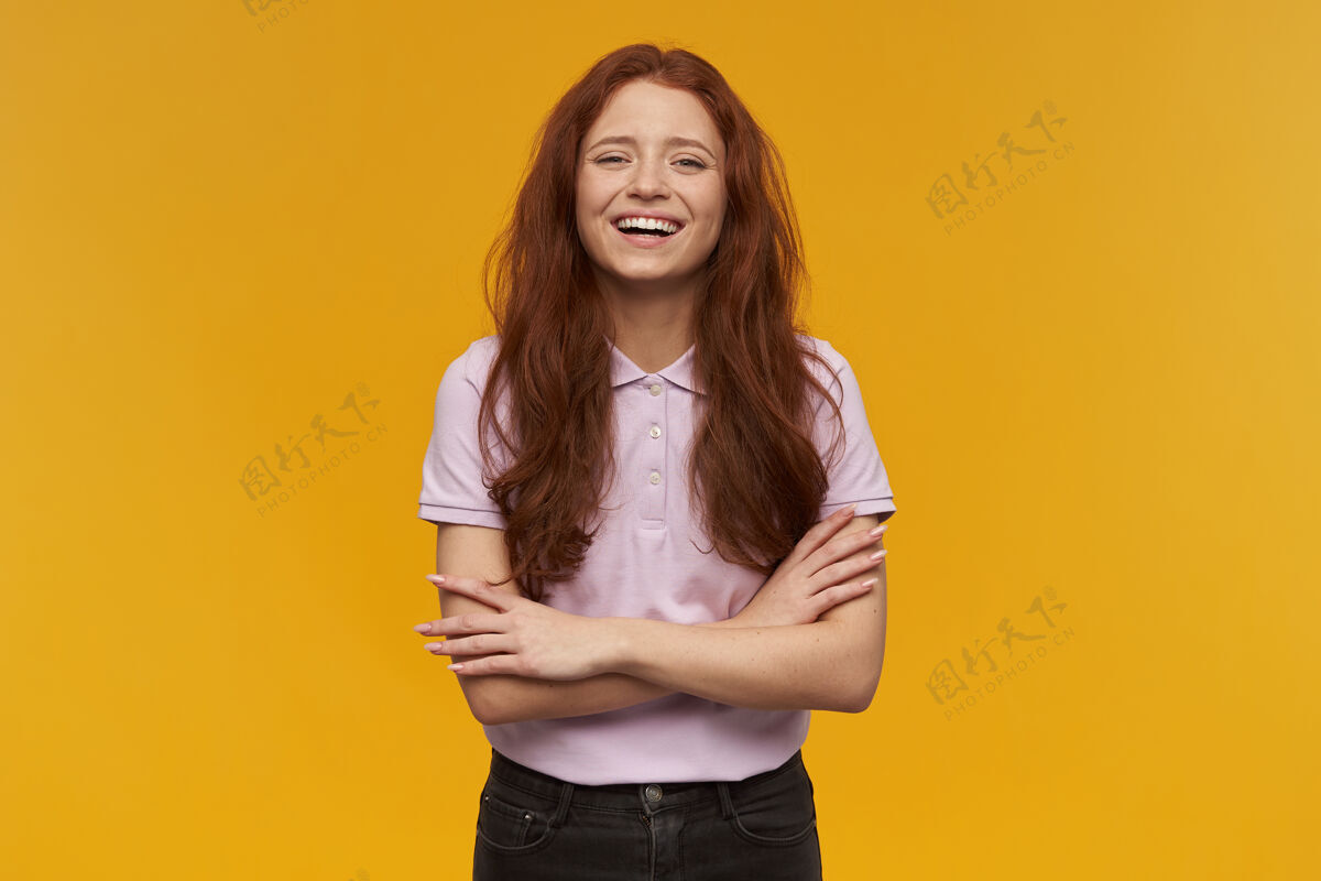 人可爱 积极向上的女人 长着一头姜黄色的头发穿着粉色的t恤人和情感的概念双臂交叉 面带微笑被隔离在橙色的墙上光青少年休闲