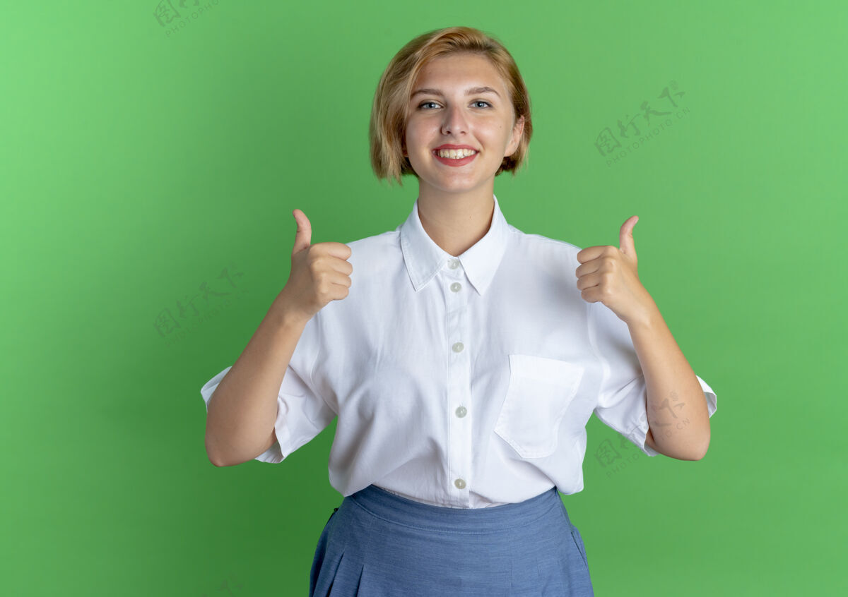 手年轻微笑的金发俄罗斯女孩竖起大拇指 两只手孤立地放在绿色背景上 留有复制空间俄国人年轻金发