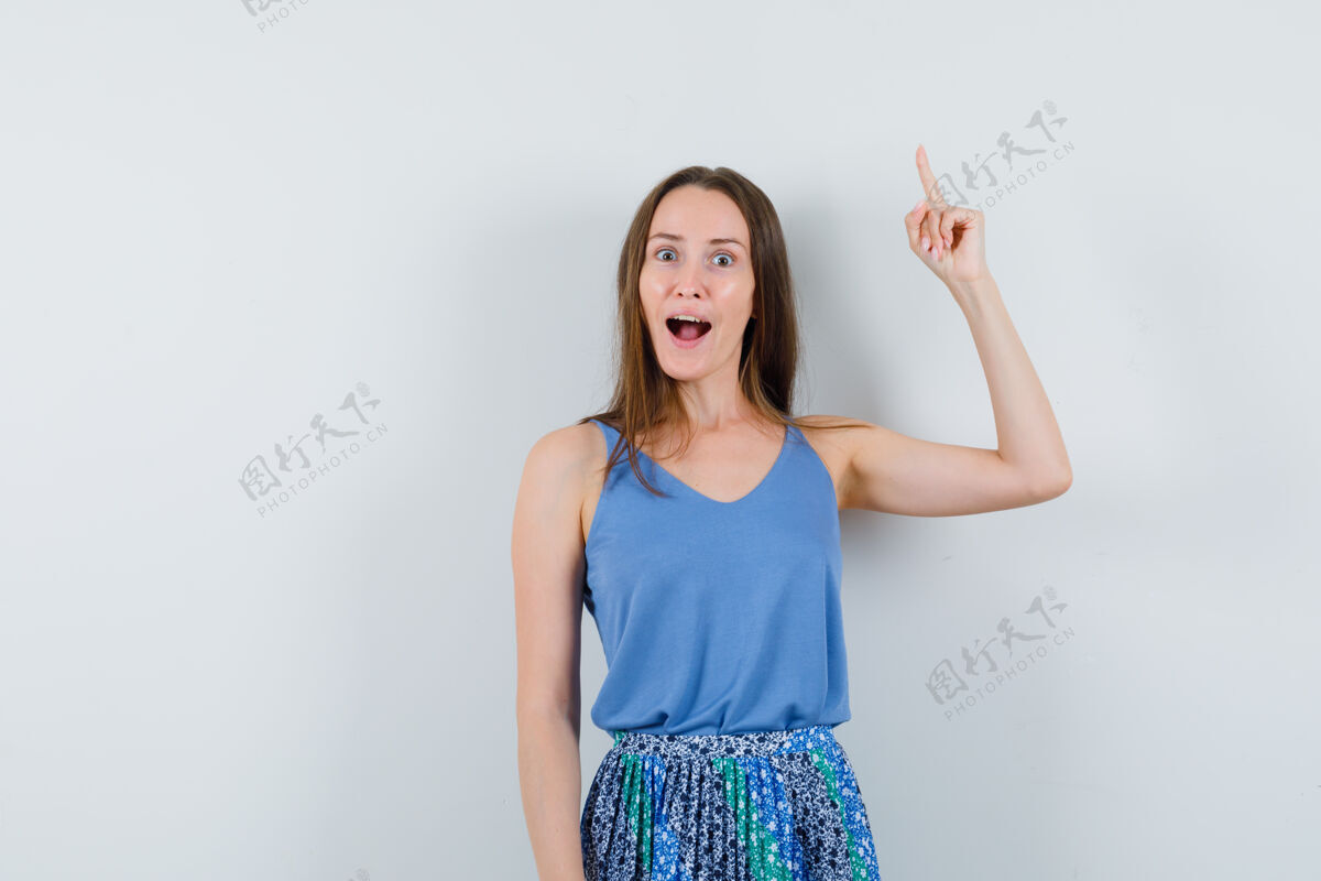 衬衫年轻的女士指着蓝色衬衫 裙子和期待惊讶 前视图文本空间观众年轻裙子