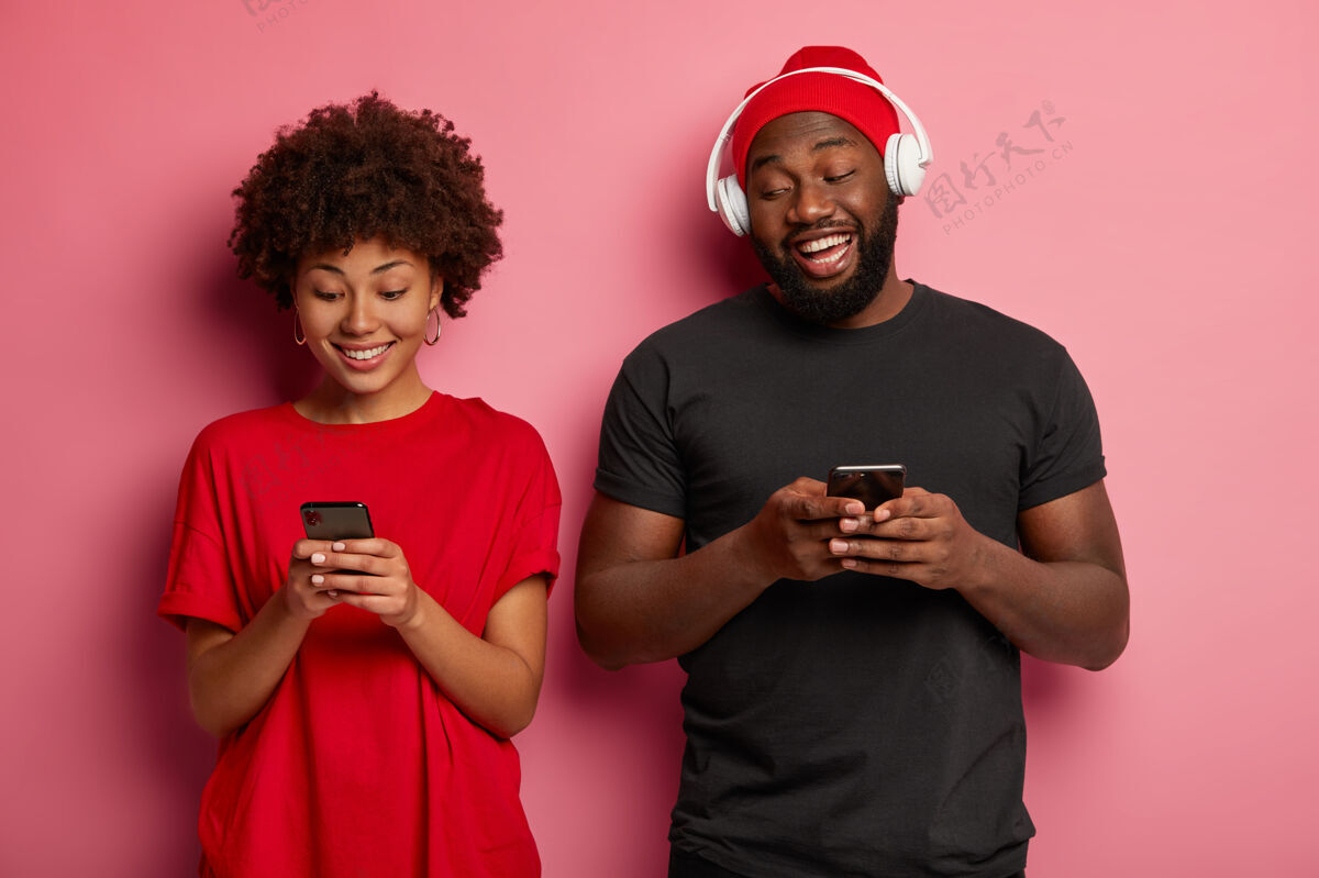 内容幸福的黑皮肤情侣站得很近 沉迷于现代科技和小玩意 玩网络游戏 心情愉快情侣男性手机