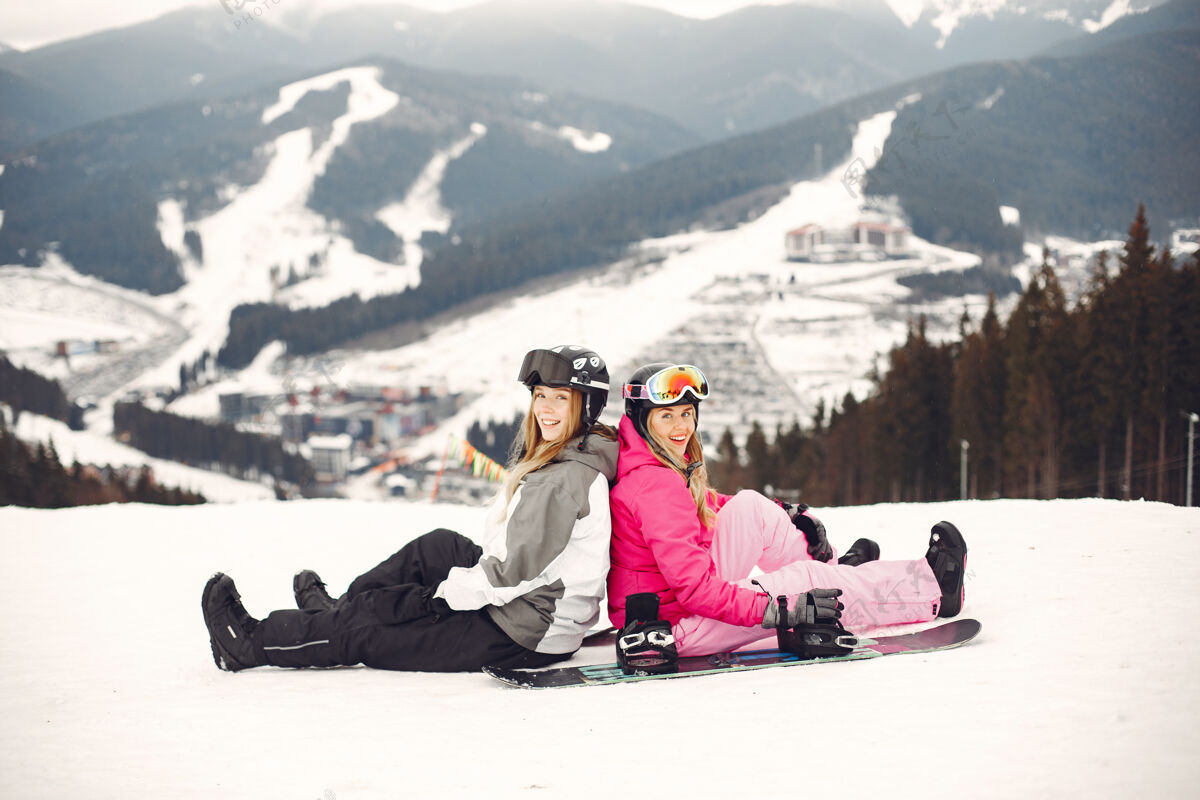 金发穿着滑雪板套装的女人在山上的运动员手拿滑雪板在地平线上关于运动的概念护目镜人雪