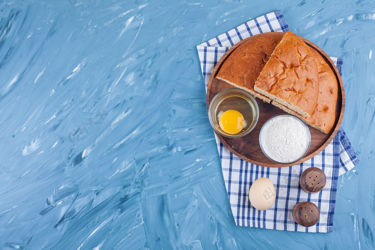 面包把面包片放在黑板上 旁边是面粉和鸡蛋 放在茶巾上 蓝色的酵母鸡蛋美味