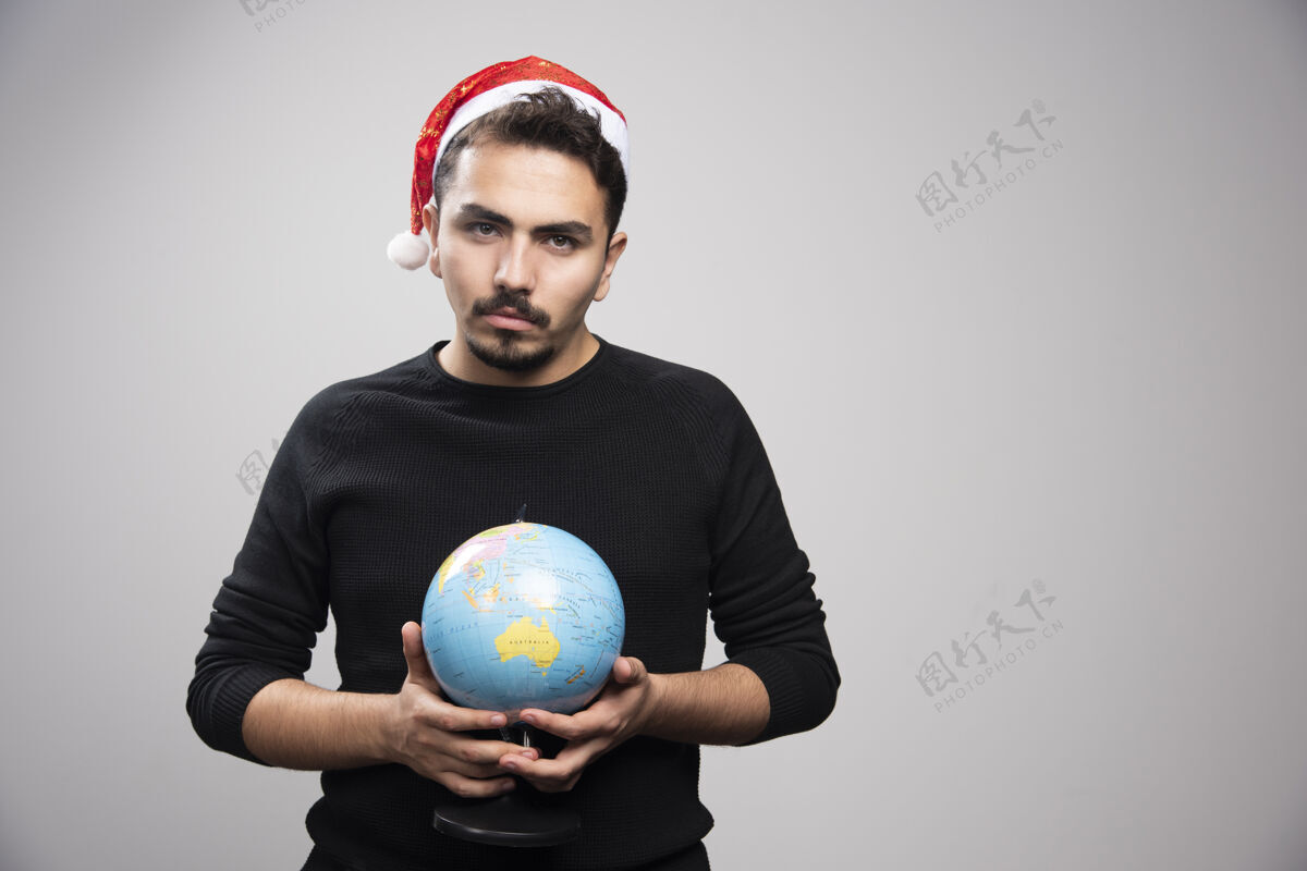 男孩戴着圣诞老人帽子拿着地球仪的愤怒男人男孩休闲圣诞老人
