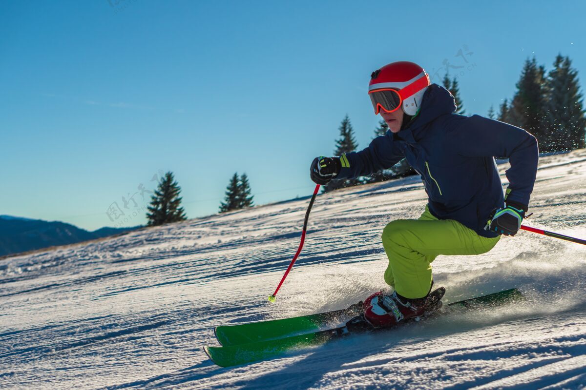 霜冻阳光明媚的日子里 一个穿着绿色裤子 戴着亮橙色头盔的男人在滑雪山电梯运动