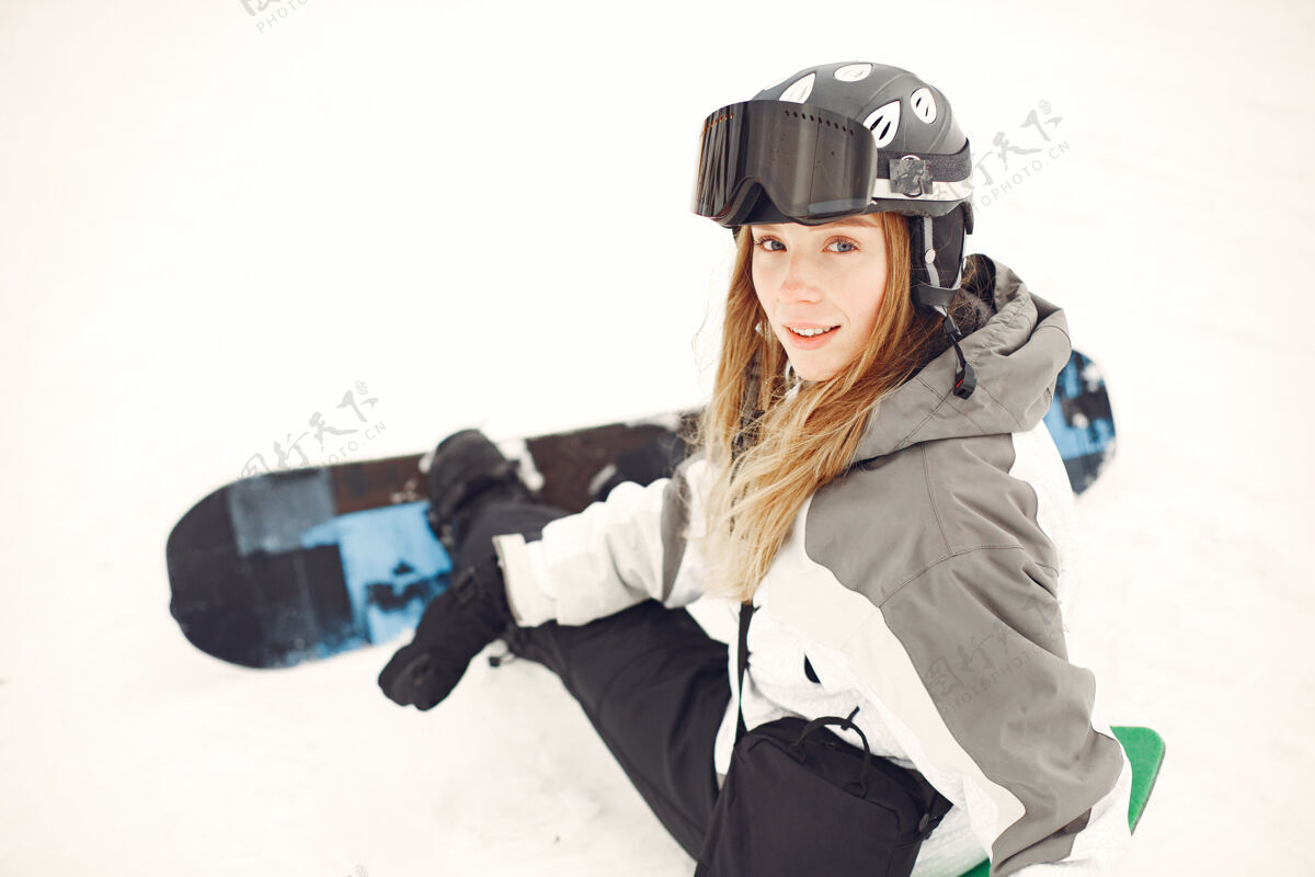 一个穿着滑雪板套装的女人在山上手拿滑雪板的运动员在地平线上关于运动的概念下雪板雪