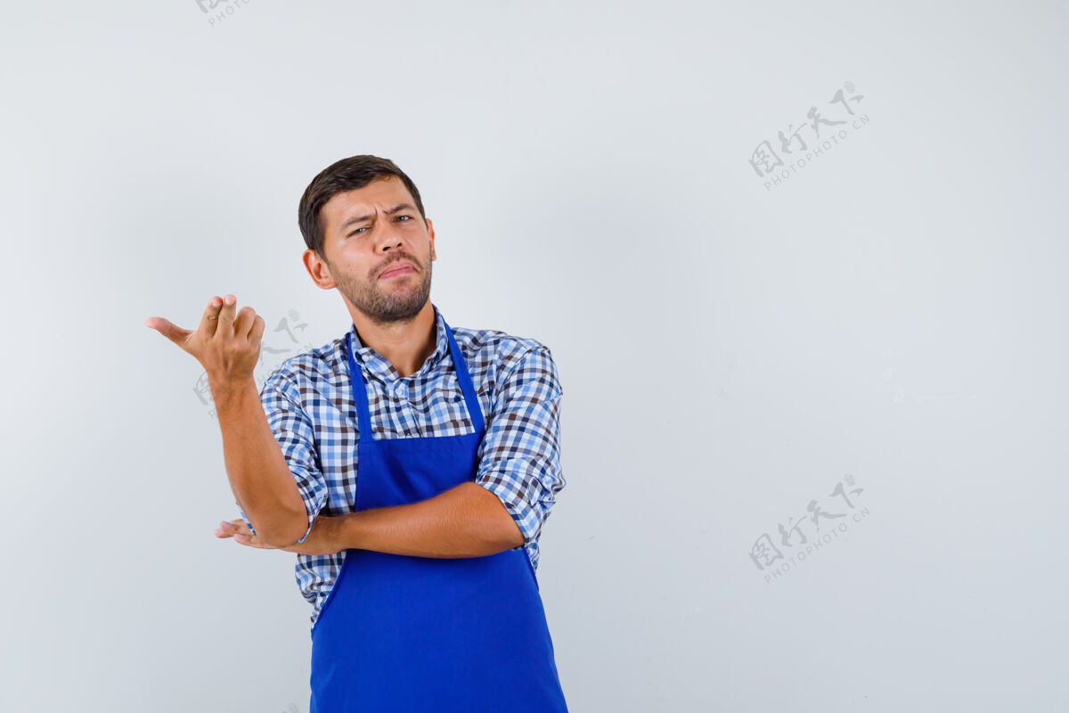 烹饪穿着蓝色围裙和衬衫的年轻男厨师厨师帅哥衬衫