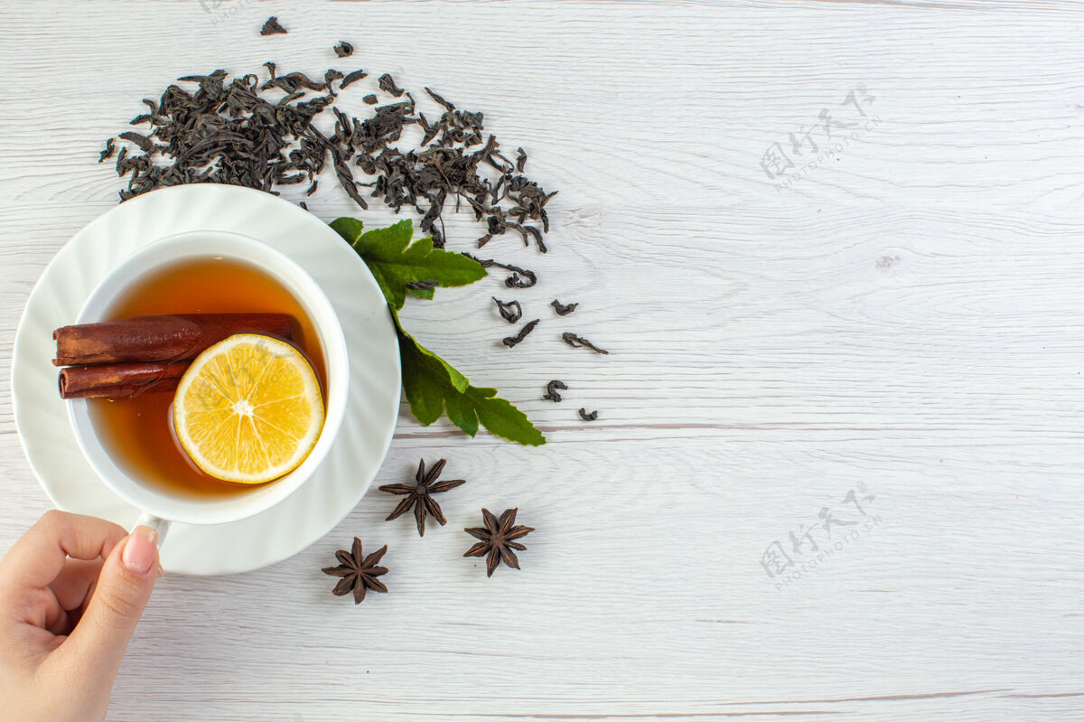 干的手拿红茶在一个白色的杯子里绕着干茶和叶子早晨杯子茶