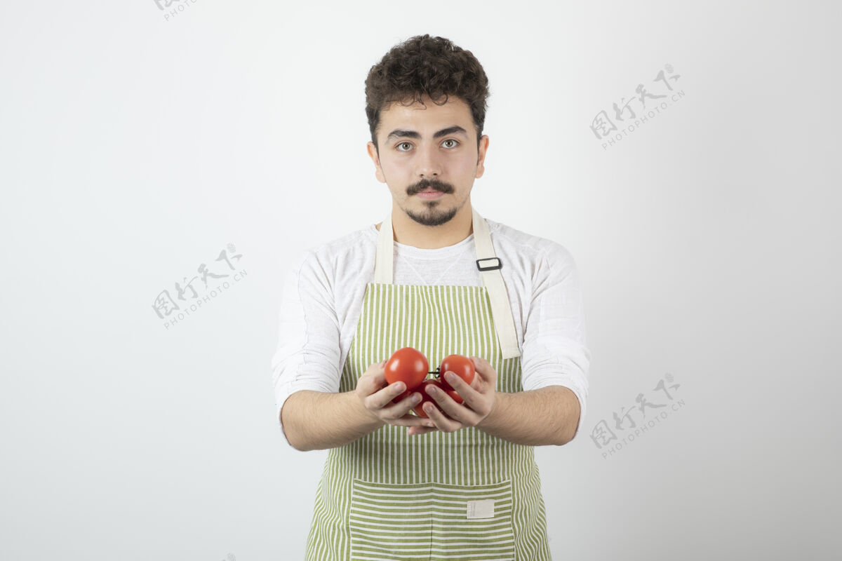 肖像年轻帅哥拿着有机西红柿直视镜头蔬菜西红柿手势