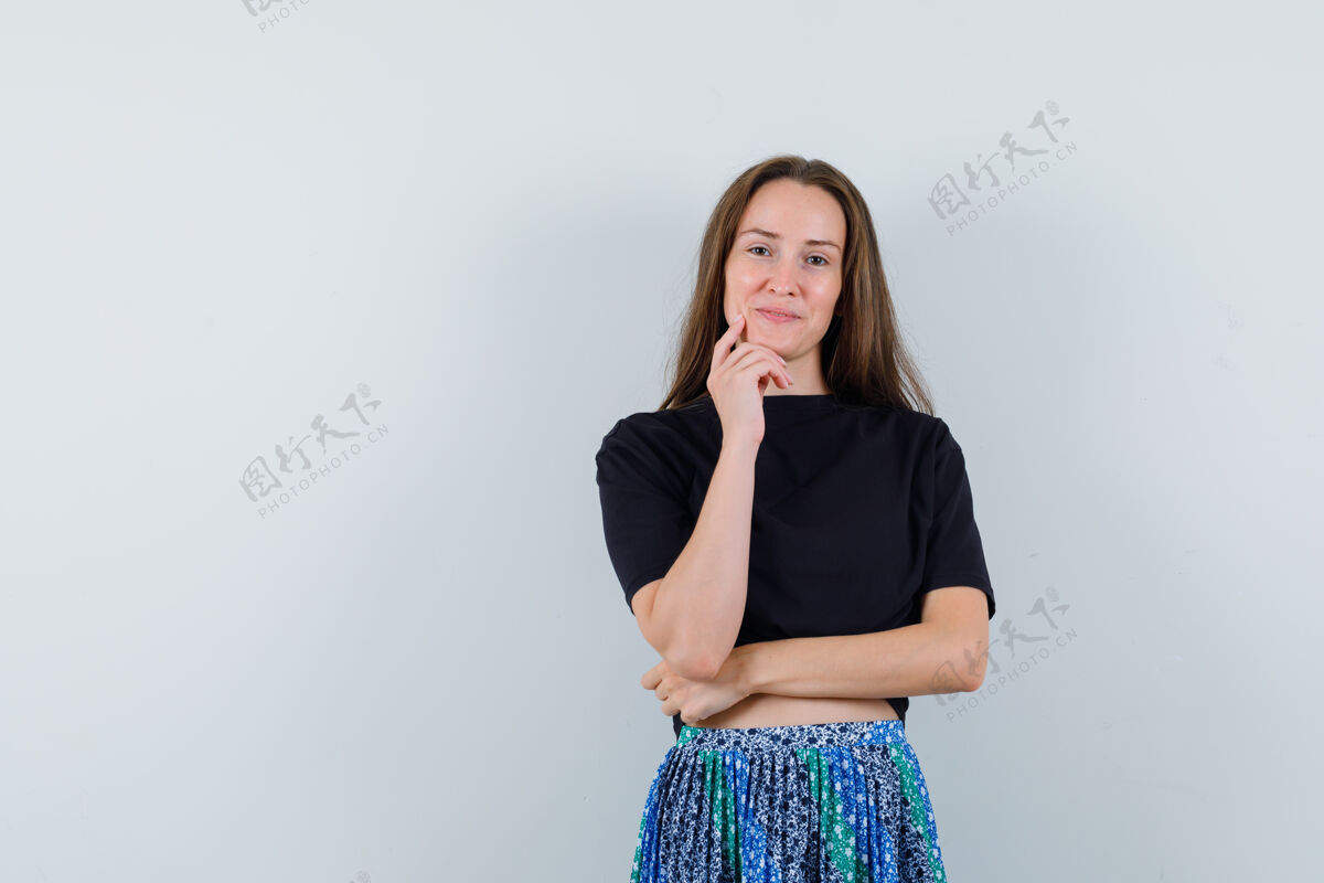 干净一位年轻女子 手托下巴 身穿黑色t恤和蓝色裙子 在镜头前摆出迷人的姿势完美健康女性