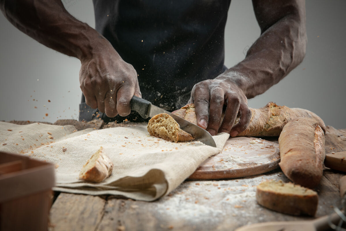 男性非洲裔美国人用菜刀切新鲜面包的特写镜头刀身体面包