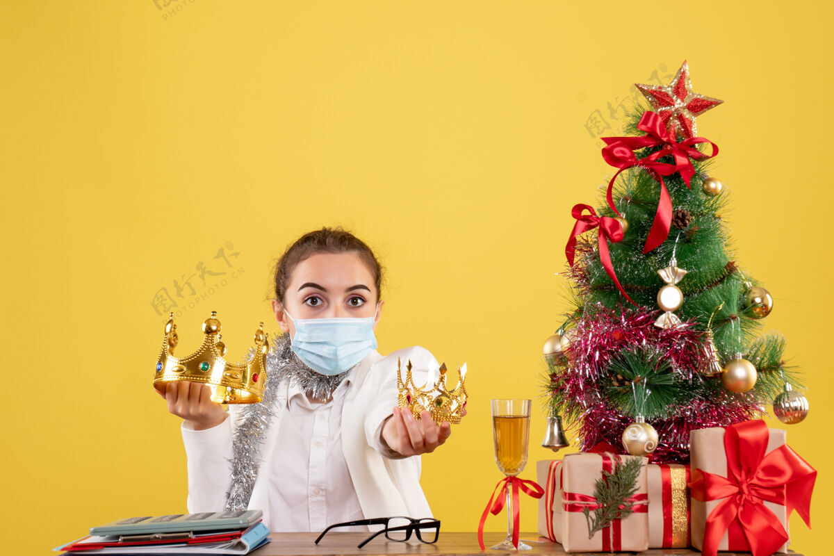圣诞节正面图：戴着无菌口罩戴着王冠的女医生病毒面具举行
