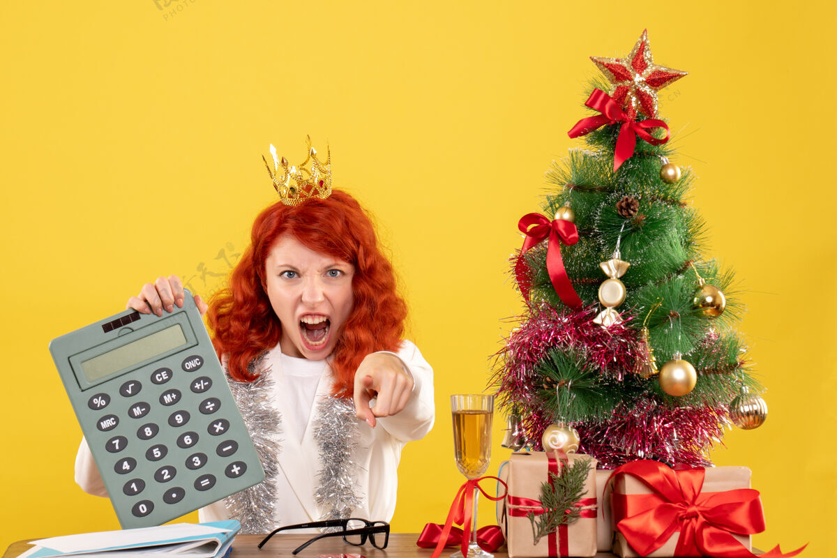 圣诞前视图女医生拿着计算器围着圣诞礼物和圣诞树年节日计算器