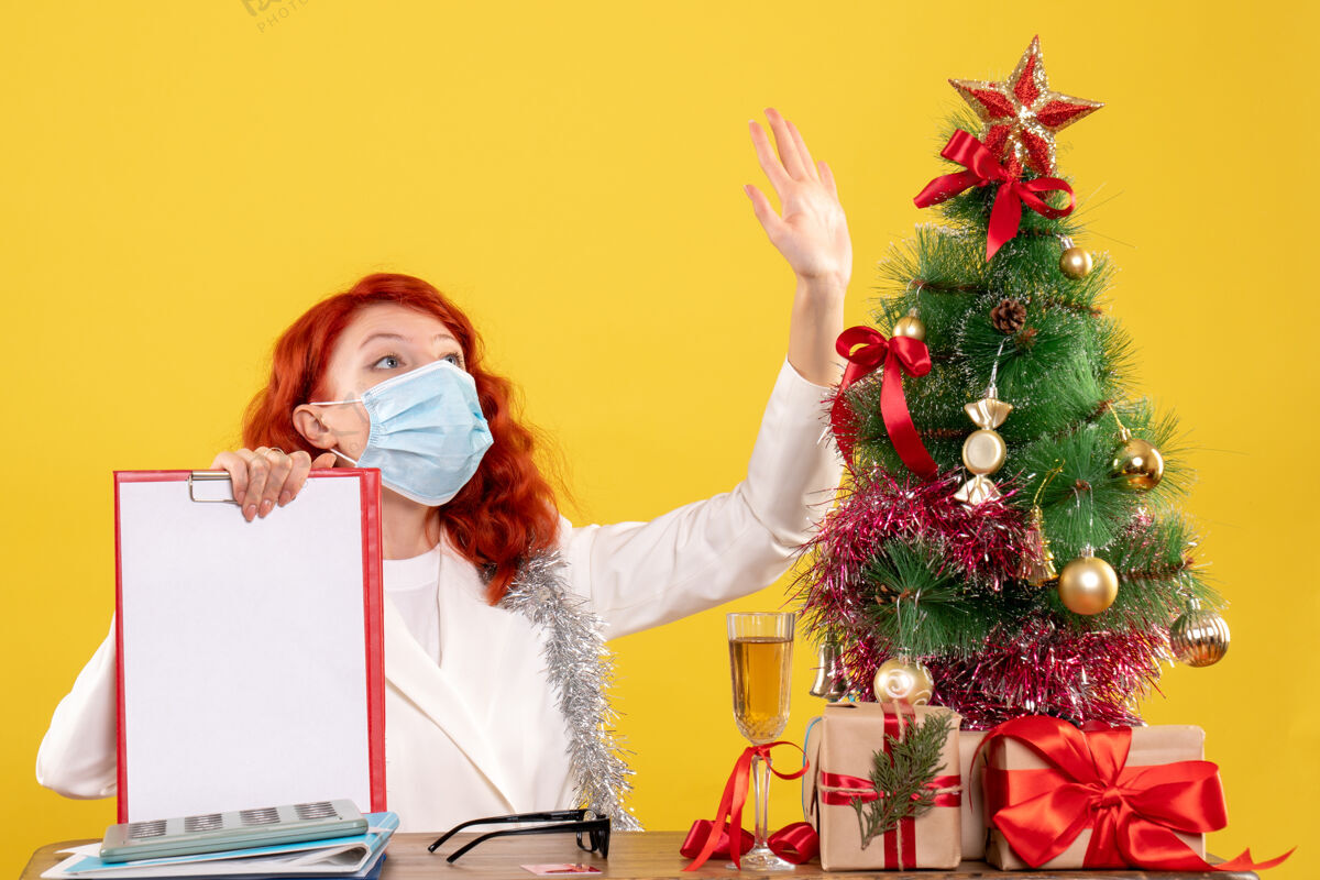 病毒前视图女医生围绕圣诞树和礼物坐在面具人花束面具