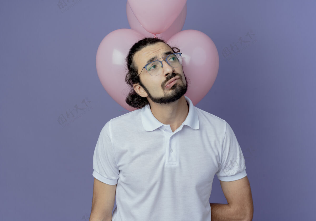 伤心看着身边愁眉苦脸的帅哥戴着眼镜站在气球前孤立的紫色背景上帅哥站侧身