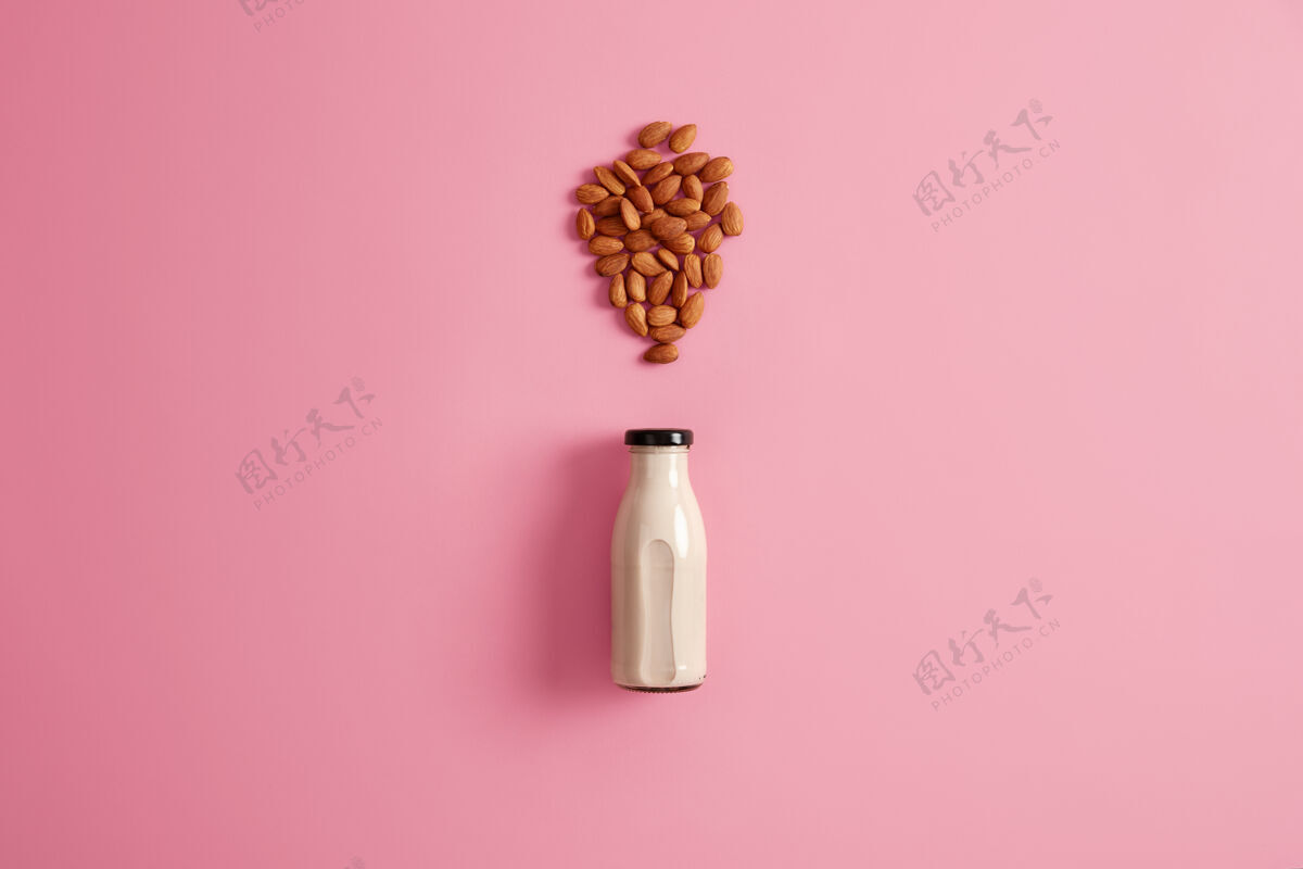 营养用玻璃瓶装的新鲜杏仁奶代替素食者的奶制品玫瑰色背景 顶视图健康的素食天然饮料饮食 保健 适当的营养概念早餐乳制品顶部