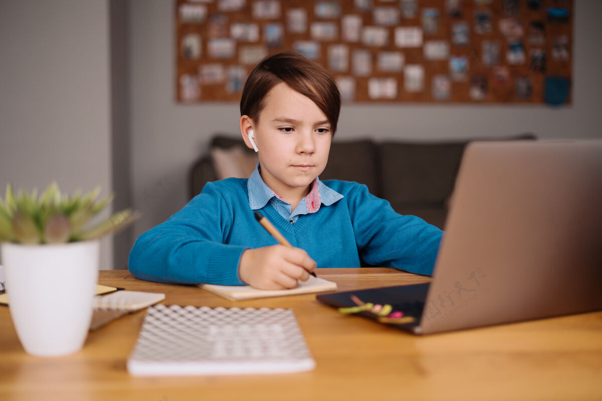 显微镜一个未成年男孩用笔记本电脑和他的老师打视频电话 在线上课 做笔记知识视频通话回到学校
